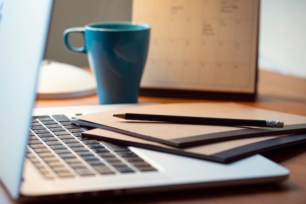 Ordinateur portable sur un bureau d'affaires en bois moderne avec un bloc-notes et un stylo.