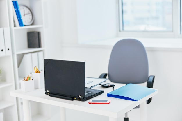 Un ordinateur portable sur un bureau avec un dossier bleu sur la table