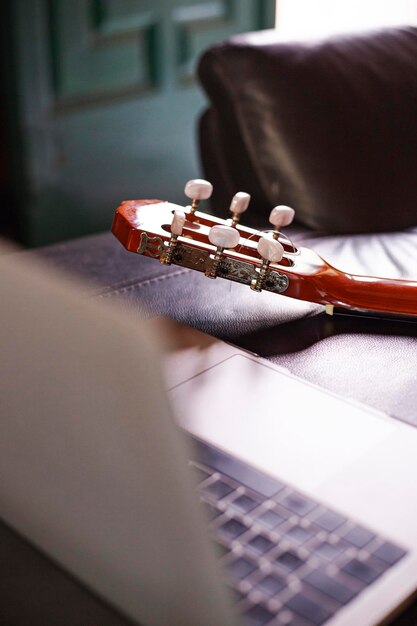 Photo un ordinateur portable sur le canapé pour apprendre à jouer de la guitare en ligne