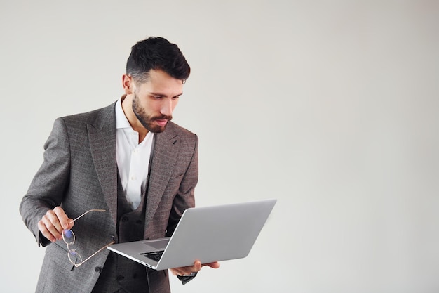 Avec ordinateur portable dans les mains Jeune homme d'affaires élégant en costume à l'intérieur Conception du succès