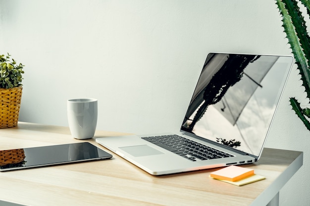 Ordinateur portable dans une pièce lumineuse sur table de travail avec fournitures de bureau