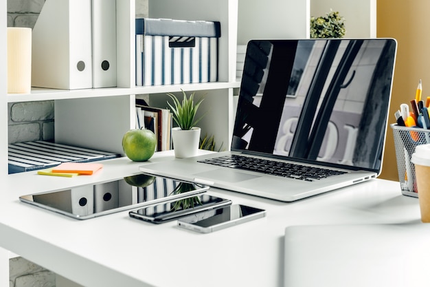 Ordinateur portable dans une salle lumineuse sur une table de travail avec des fournitures de bureau