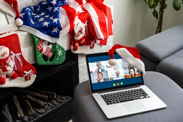 Ordinateur portable debout sur une table avec un cadeau et un bonnet de Noel dans une chambre confortable, Joyeux Noël et Bonne Année