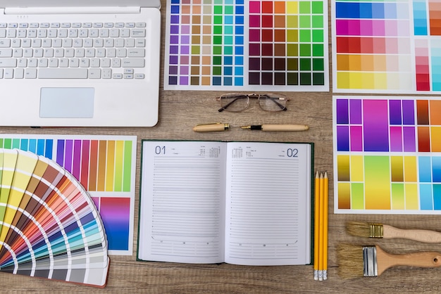 Ordinateur portable avec des échantillons de couleur sur une table en bois pour la rénovation domiciliaire