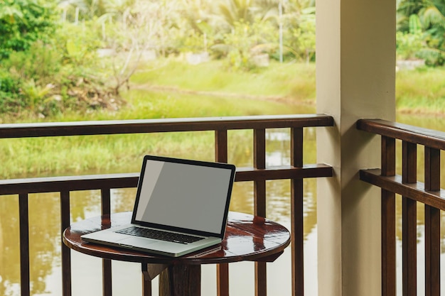 Ordinateur portable avec écran blanc debout sur une table sur une terrasse de cabine