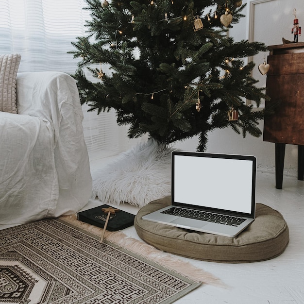 Ordinateur portable avec écran blanc sur oreiller décoré de sapin de Noël Lumineux confortable élégant bureau à domicile espace de travail design d'intérieur Travail esthétique à la maison concept Modèle de marque de site Web de blog