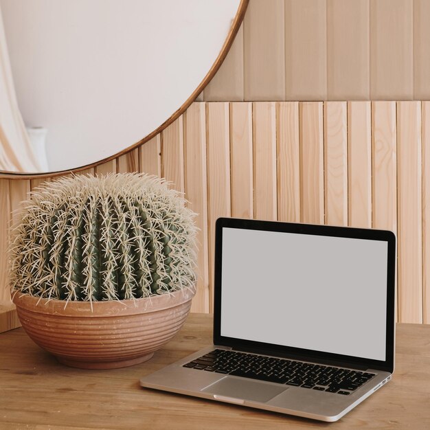 Ordinateur portable avec écran d'espace de copie et cactus sur table en bois