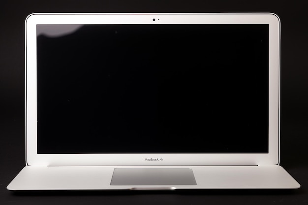 Un ordinateur portable avec un écran noir vide sur une table blanche
