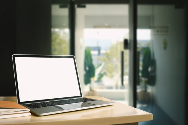 Ordinateur portable avec écran vide sur table en bois au bureau à domicile.