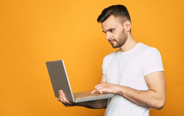 Un ordinateur portable entre les mains d'un programmeur avec un visage sérieux et beau à la fois qui cherche une solution au problème commun