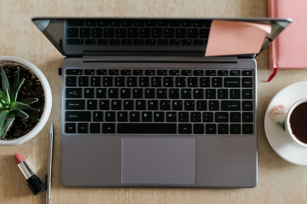 Ordinateur portable de l'espace de travail féminin, bouquet de rose rose, cahier et vue de dessus de tasse de café