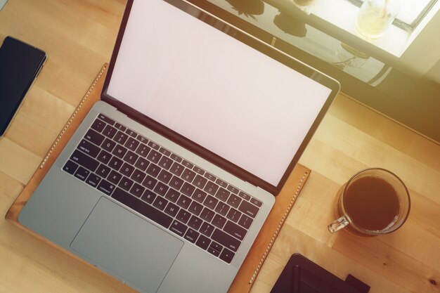 Ordinateur portable espace de travail indépendant sur un bureau en bois avec lumière de fenêtre.