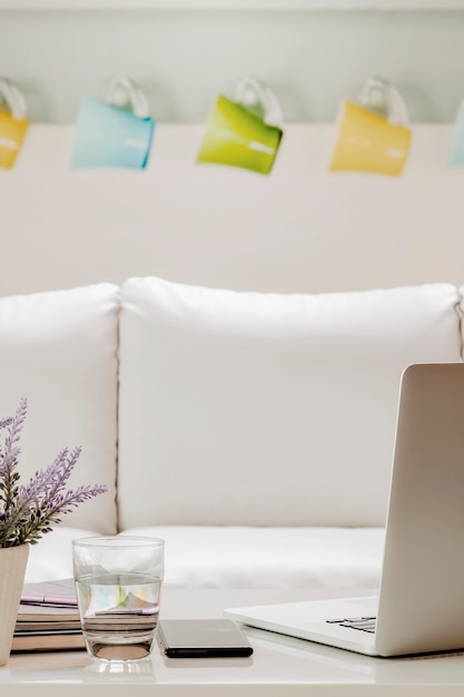 Ordinateur portable avec des fournitures sur une table en bois blanche dans le salon