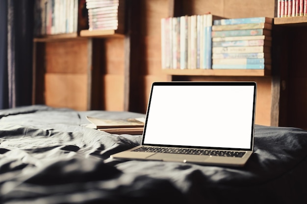 Ordinateur portable sur le lit avec lumière douce de la fenêtre Écran blanc pour votre texte publicitaire