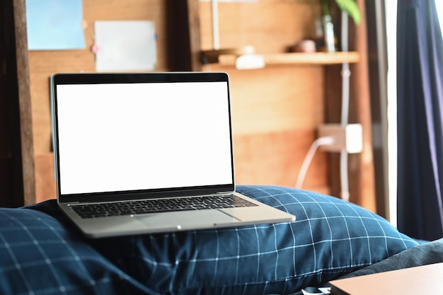 Ordinateur portable sur le lit le matin avec une lumière douce de la fenêtre Écran vide pour le texte publicitaire