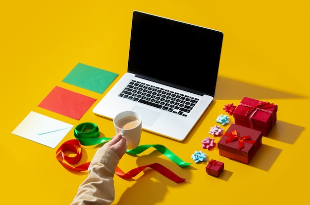 Ordinateur portable, main tenant une tasse de café et diverses choses de Noël