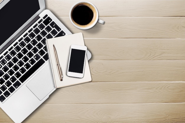 Ordinateur portable avec mobile et tasse de café sur une table en bois au bureau