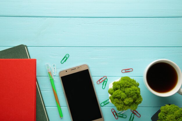 Ordinateur portable avec smartphone et tasse de café sur fond de bois bleu.