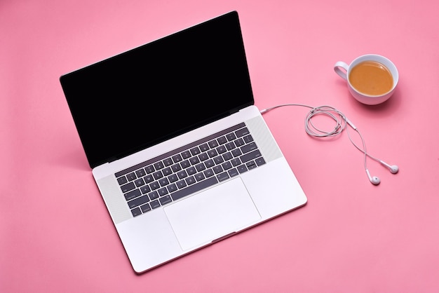 Ordinateur portable sur table blanche avec écouteurs et tasse à café. Vue d'en-haut