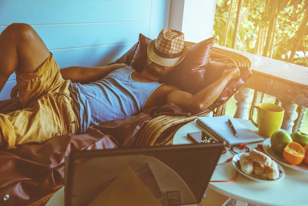 Photo un ordinateur portable sur la table contre un homme qui dort sur le balcon.