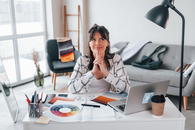 Avec un ordinateur portable sur la table La jeune travailleuse indépendante est à l'intérieur de la maison pendant la journée