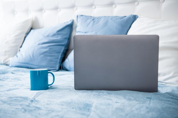 Ordinateur portable et tasse à café sur l'espace de copie du lit
