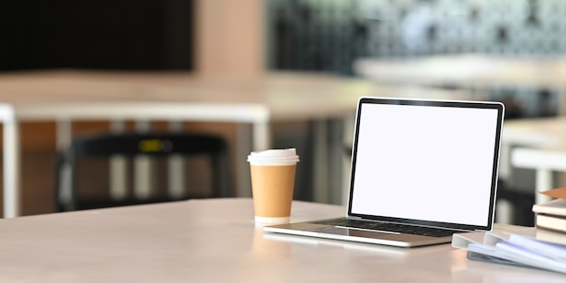 ordinateur portable, tasse de café en papier, fichier de document sur la table d'affaires avec écran vide.