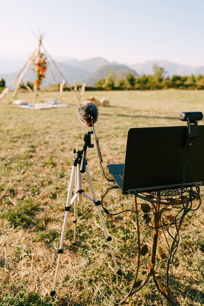 Photo un ordinateur portable avec une webcam et un microphone sur un support se tient devant une arche de mariage sur un pré vert