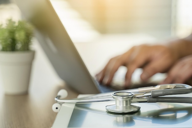 Ordinateur stéthoscope et médecin de fond utilisant un ordinateur portable au réseau médical de bureau sur l'informatique médicale électronique