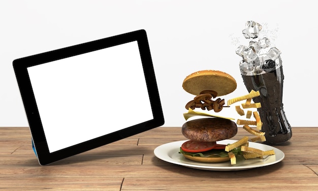 Ordinateur tablette avec un écran vide sur la table en bois avec un hamburger et un verre de cola avec