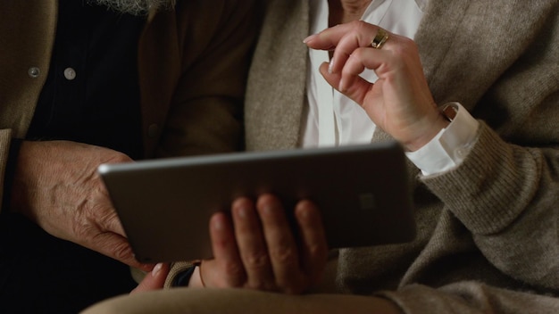 Ordinateur tablette en gros plan dans les mains d'un couple de personnes âgées à l'intérieur Une vieille famille inconnue utilisant l'écran d'un appareil numérique à l'extérieur Des personnes âgées lisant des nouvelles, regardant des photos, discutant en ligne, surfant sur Internet sur un pad