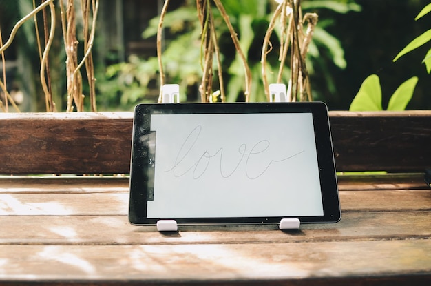 Ordinateur tablette qui dit l'amour sur une table en bois à l'extérieur