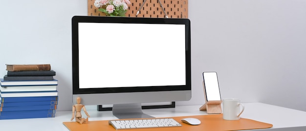 Ordinateur, téléphone intelligent, livres et fournitures de bureau sur un bureau blanc dans un bureau moderne.