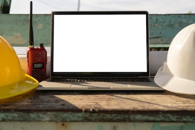 Photo ordinateurs portables de casque de sécurité blanc et jaune placés sur une table