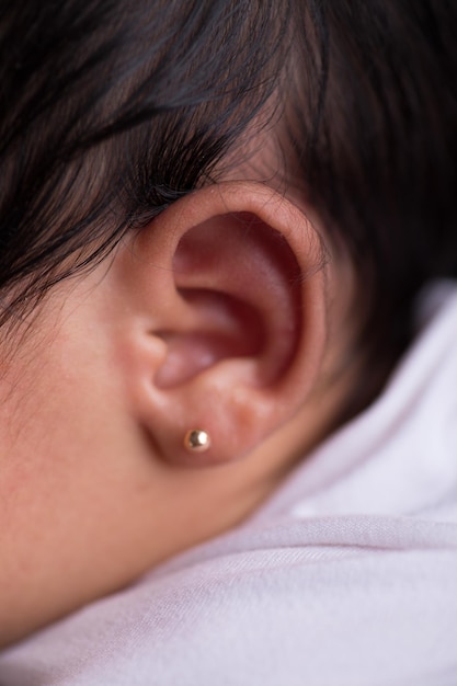 L'oreille d'une femme avec une boucle d'oreille en or.