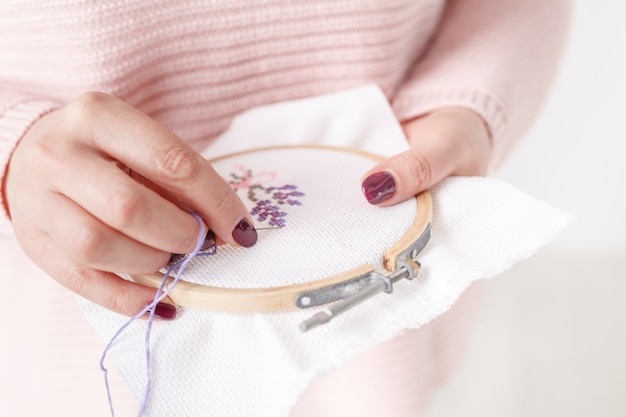 Oreiller au point de croix dans les mains des femmes