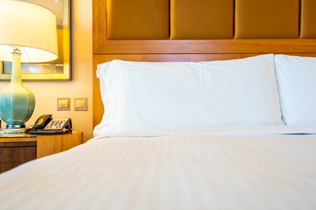 Oreiller blanc confortable sur le lit avec décoration de lampe de table dans la chambre d&#39;hôtel