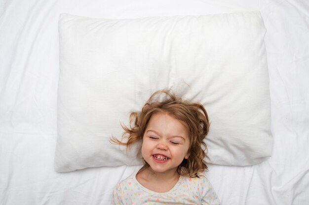 Oreiller blanc maquette avec une fille souriante dans le lit
