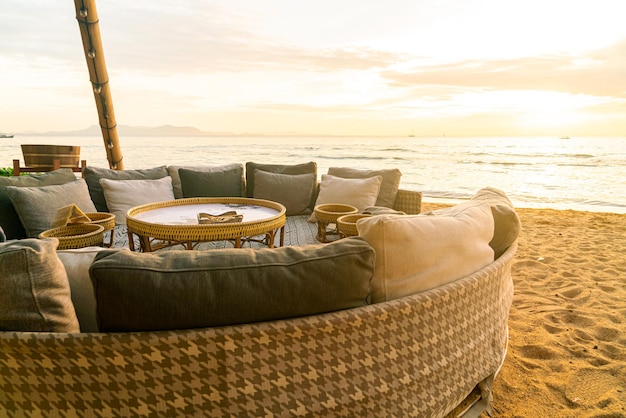 oreillers sur une chaise longue de patio extérieur sur la plage avec fond de coucher de soleil