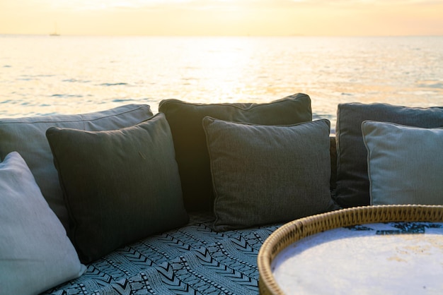 oreillers sur une chaise longue de patio extérieur sur la plage avec fond de coucher de soleil