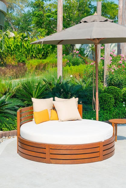 oreillers sur une chaise de patio extérieur avec parasol dans le jardin