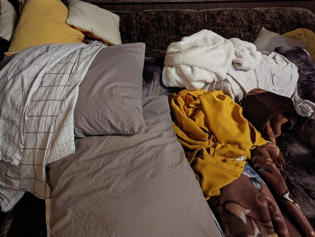 oreillers, couvertures, couvertures et linge de lit éparpillés dans la chambre