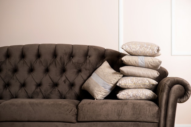Oreillers crème beige avec ornements sur canapé noir dans l&#39;appartement