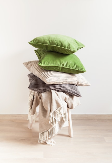 Oreillers gris et verts sur une chaise blanche