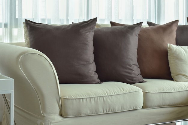 Photo oreillers marron foncé posant sur un canapé de couleur beige