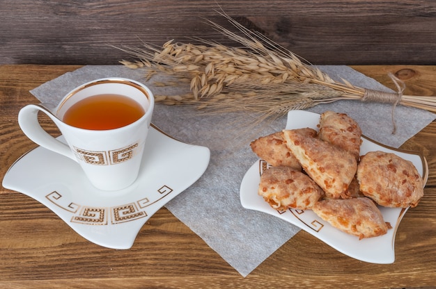 Oreilles de blé, une tasse de thé et des biscuits sur un fond en bois