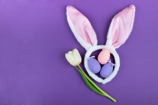 Oreilles et oeufs de lapin de carnaval avec décor sur une surface violette