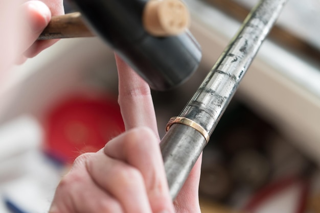 Orfèvre travaillant sur un anneau inachevé avec son marteau