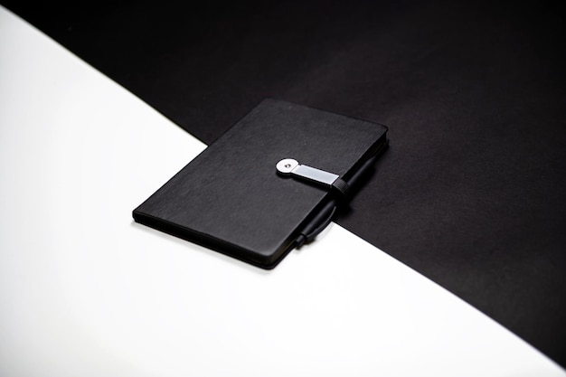 Organisateur noir ou cahier avec stylo sur fond noir et blanc à deux couleurs espace de copie de maquette