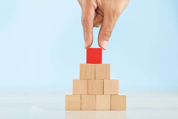 Organiser à la main l’empilement de blocs de bois rouge en tant qu’escalier, avec le concept d’une entreprise prospère en passe de réussir.